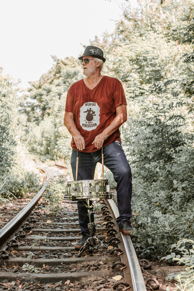 Drummer of live wedding band posing on train tracks