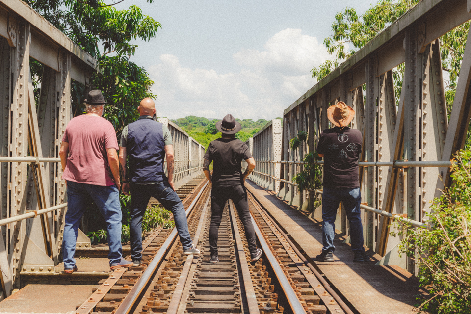 Rock band walking along railway line in dramatic sunlight
